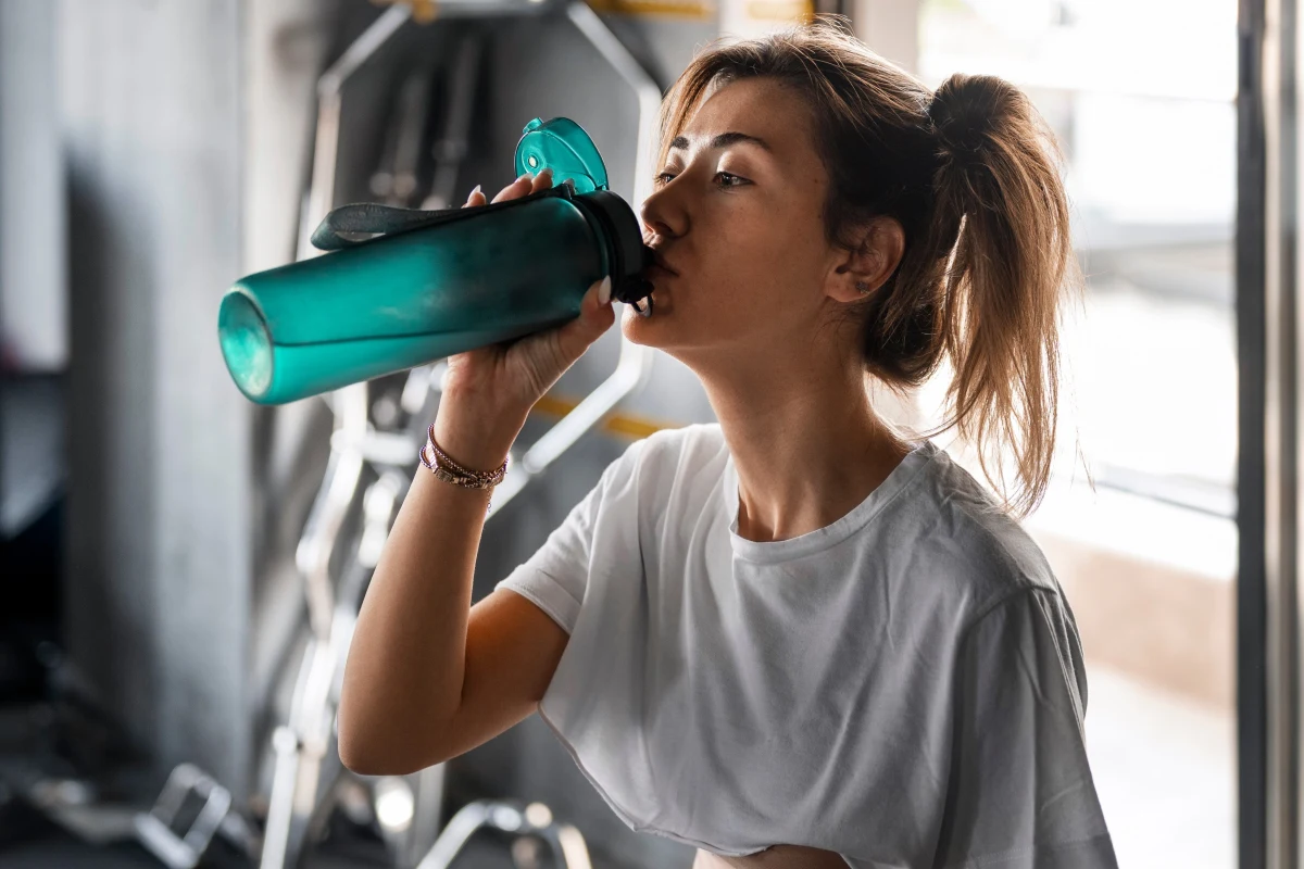 Woman drinking from a teal shaker after exercise