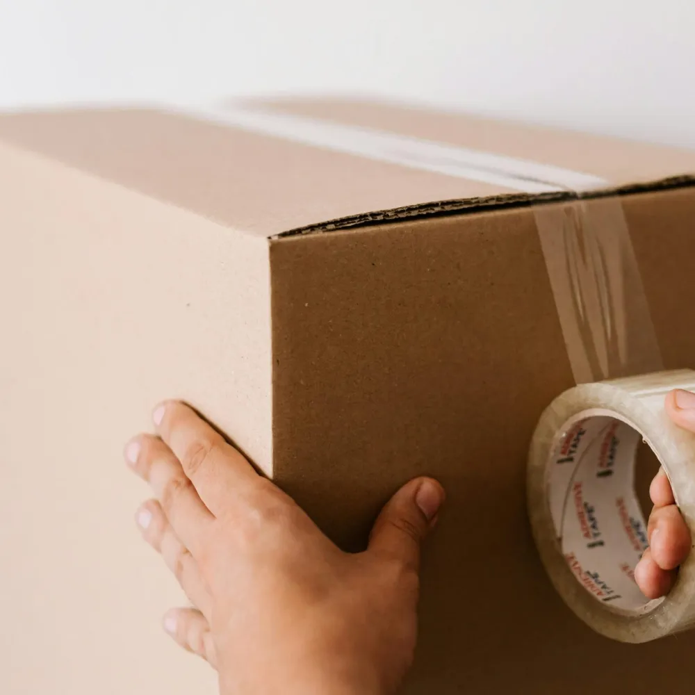 Hands carefully sealing a protective cardboard parcel